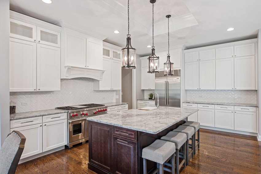Kitchen with island, hanging lights, countertop, white cabinetry, and wood floor