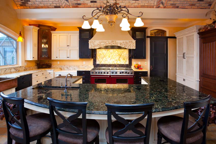 Kitchen with center island, labradorite countertop, range hood, chairs, and cabinets
