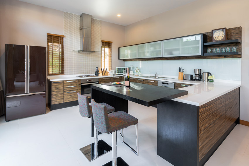 Kitchen with center island, range hood, backsplash, white flooring, and glass cabinets