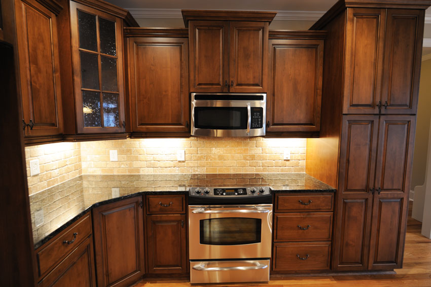 Kitchen with dark oak cabinets, countertop, backsplash, and wood floor