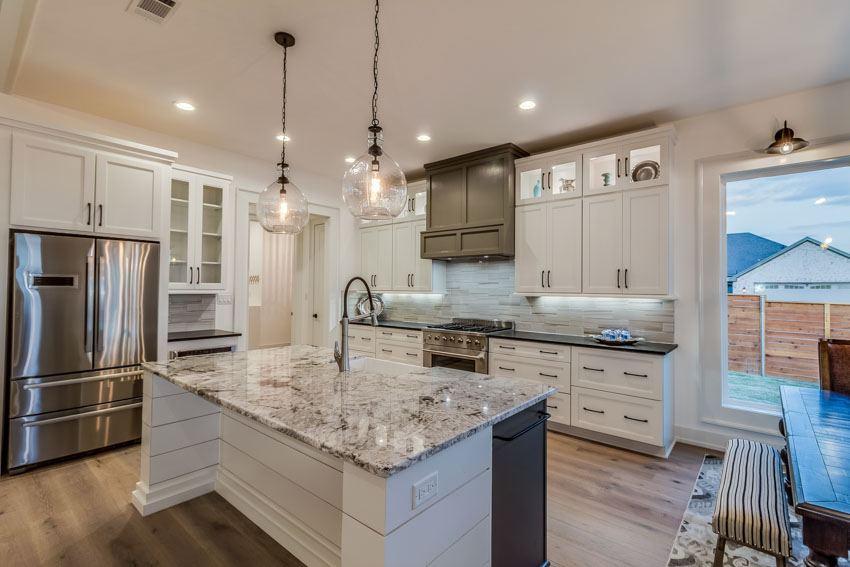 Kitchen with granite countertops, pendant lights, wood floor, and white cabinets