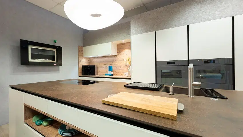 Kitchen with grey walls large pendant light and a large kitchen island with copper countertops sink and cooktop
