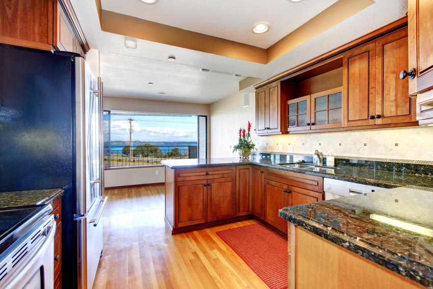 Kitchen with labradorite countertop, wood floor, cabinets, and backsplash