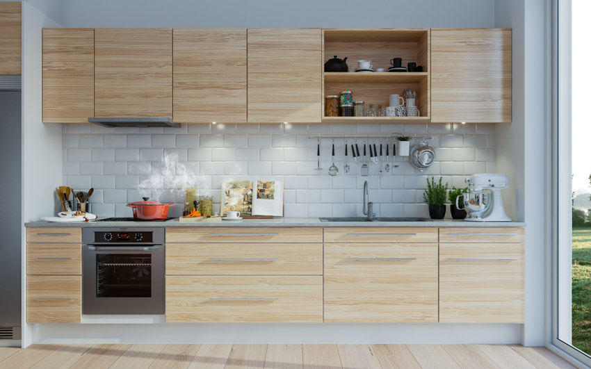Kitchen with light wood cabinets, oven, backsplash, and shelves