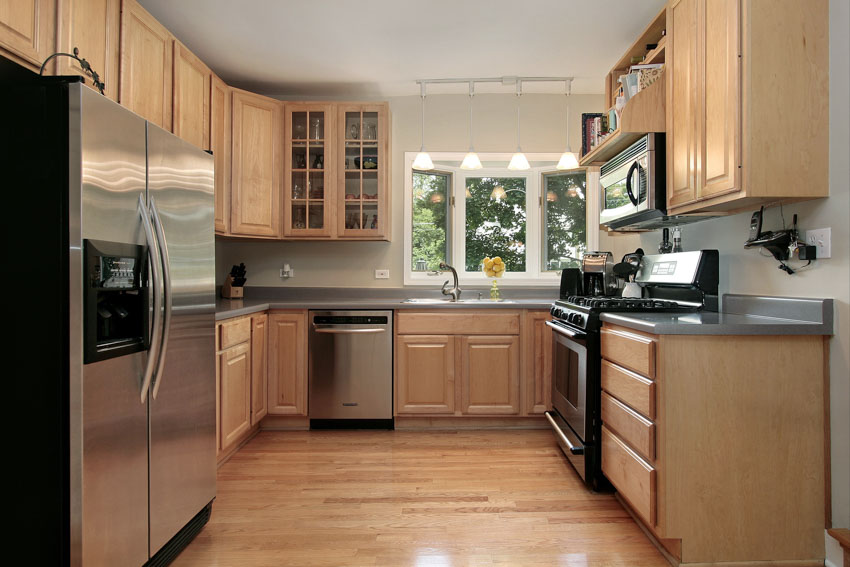 Kitchen with oak cabinets, appliances, wood flooring, drawers, countertop, and window