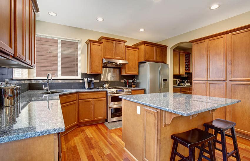 Kitchen with honeyed oak wood cabinets dark grey backsplash grey granite counters