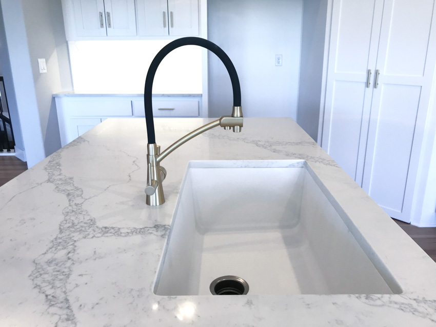 Kitchen with honed quartzite countertop, sink, and white cabinets