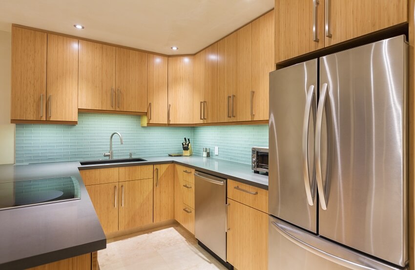 Kitchen with sky blue glass tile backsplash and grey countertops with cooktop