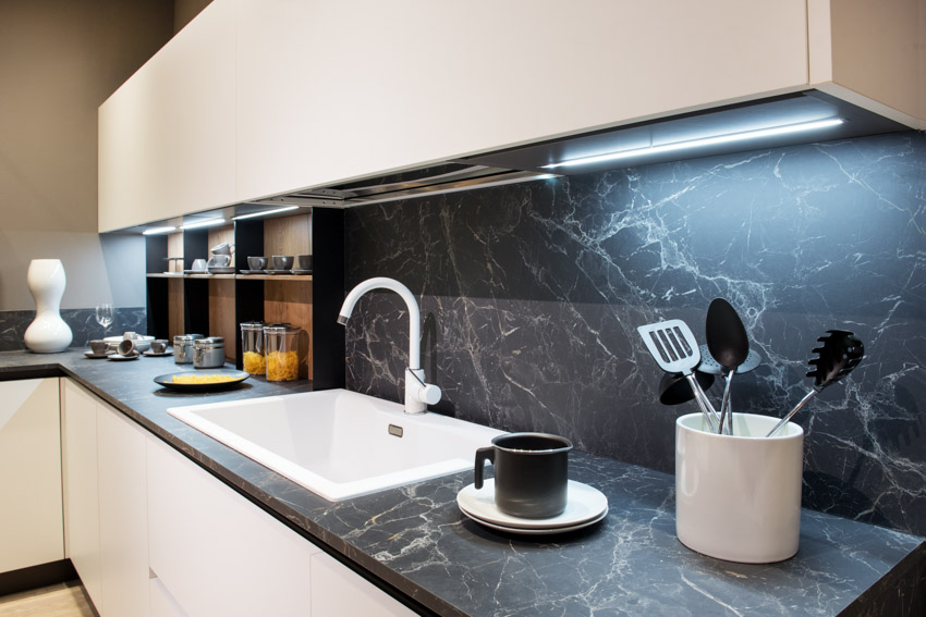 Kitchen with soapstone backsplash, countertop, sink, faucet, and under cabinet lighting