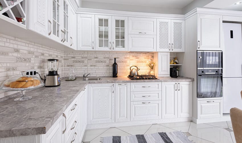 Kitchen with white cabinets brick backsplash wine storage tile floors lighting fixtures and honed granite countertops