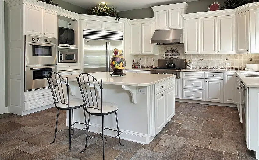 Kitchen with white cabinets stainless steel appliance cleft slate tile floors and a kitchen island with white countertops and chairs