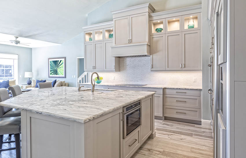 Kitchen with white honed granite countertops island white cabinets wood look tile floor