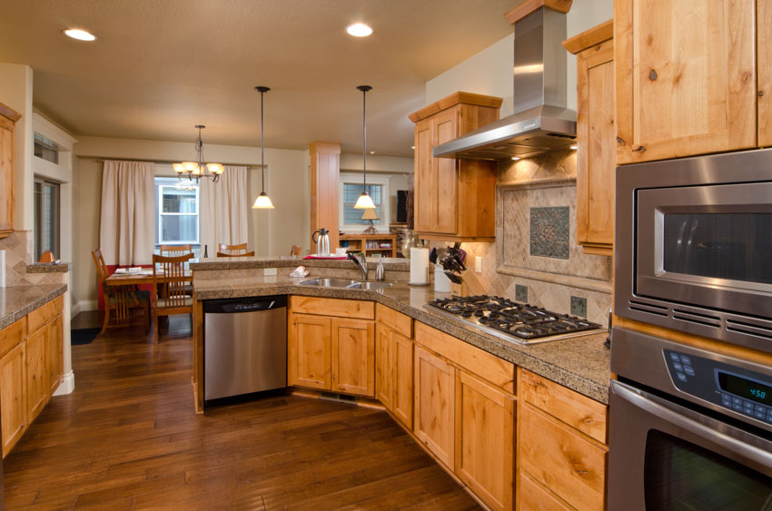 Kitchen with oak cabinetry, plank floors, recessed lights