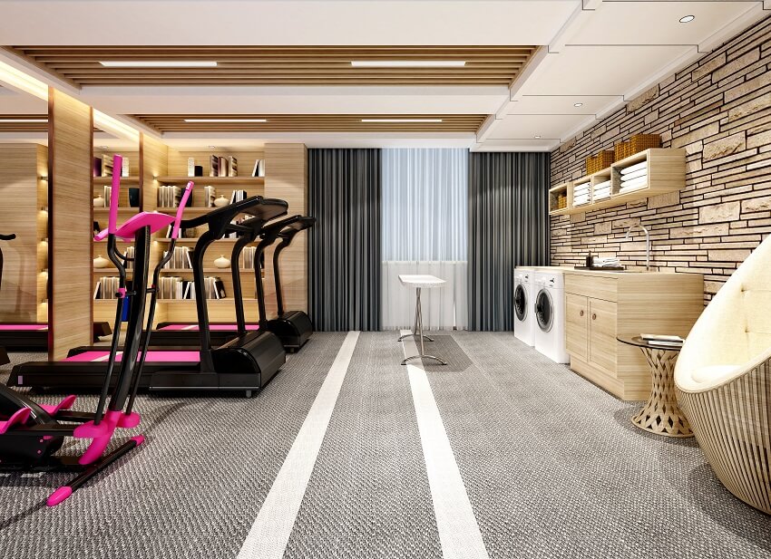Laundry room and home gym with carpeted floors wood furniture bookshelves stone wall ceiling panels lighting fixtures and black and pink gym equipment
