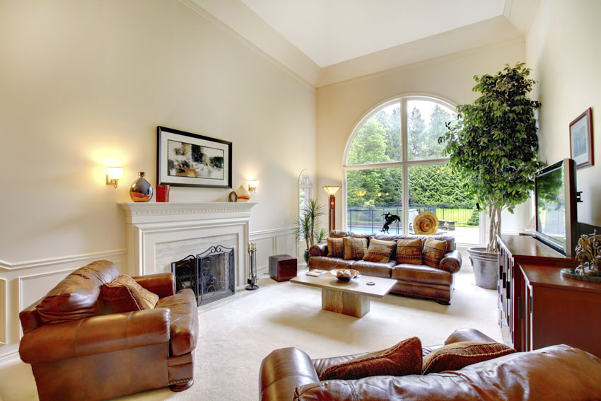 Living room space with arched window, brown leather chairs, and fireplace