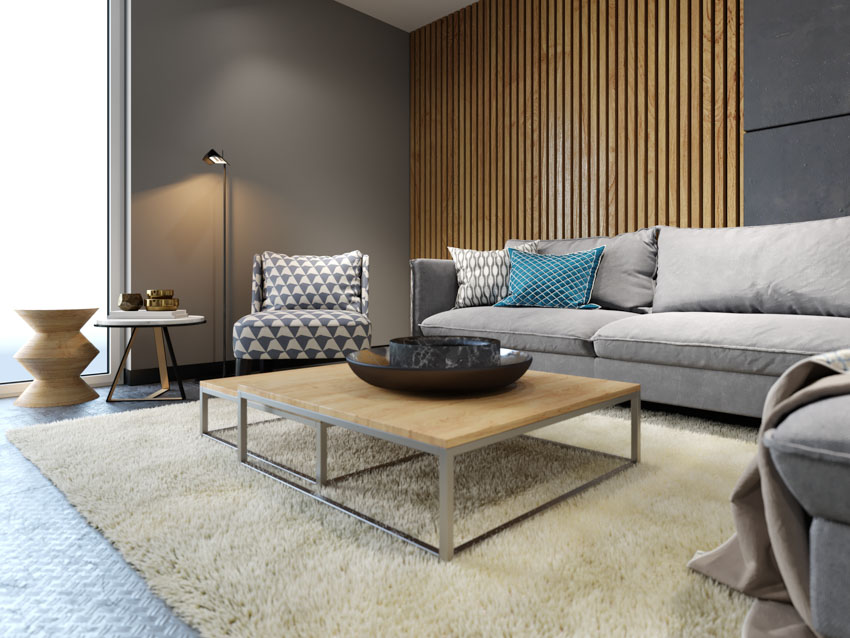 Living room with carpet, couch, floor lamp, wood slat wall, and coffee table