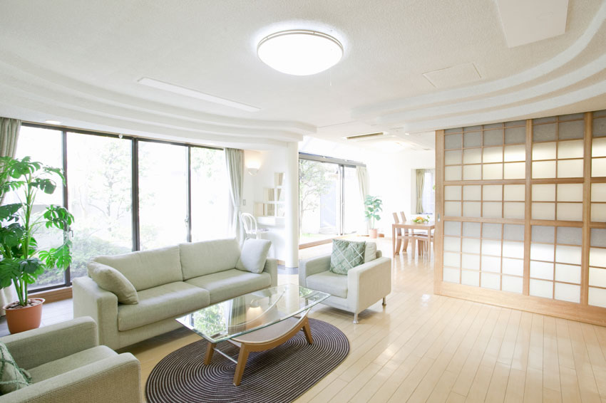 Room with ceiling light, light grey couch, arm chairs and wood divider