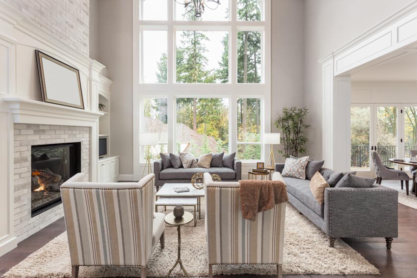 Room with high ceiling, tall windows, sofa chairs, fireplace, and carpet