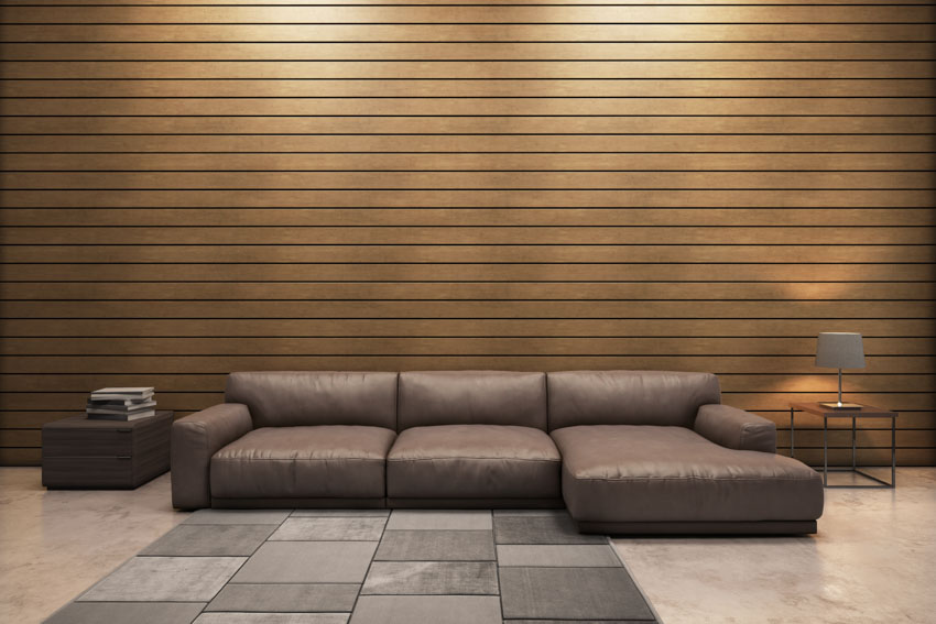 Living room with horizontal wood slat wall, leather couch, and lamp