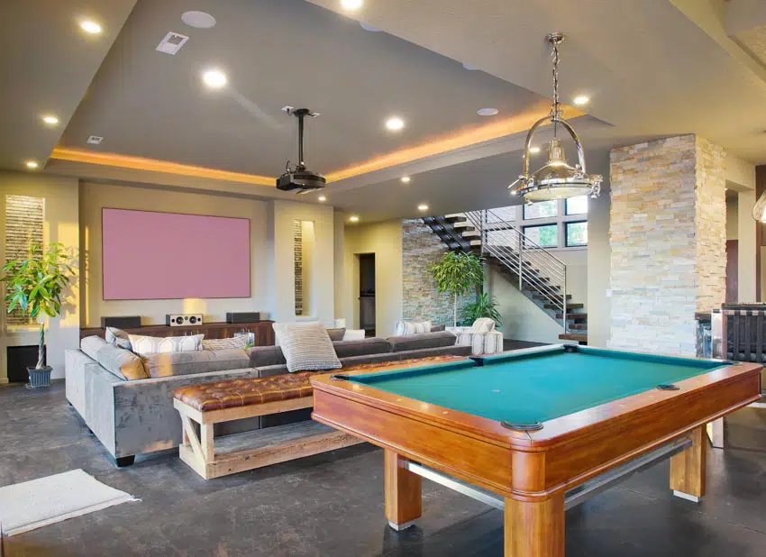 Living space with pool game table, tray ceiling, lighting fixtures, couch, and indoor plants