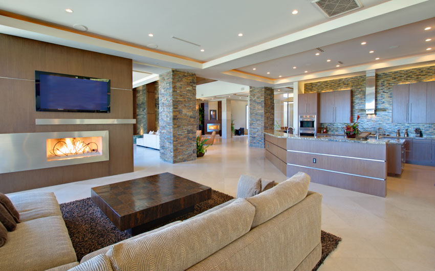 Living room with recessed lighting fixtures, couch, fireplace, television, and pillars