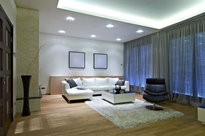 Living room with recessed lights, white couch, rug, wood floor, and window curtains