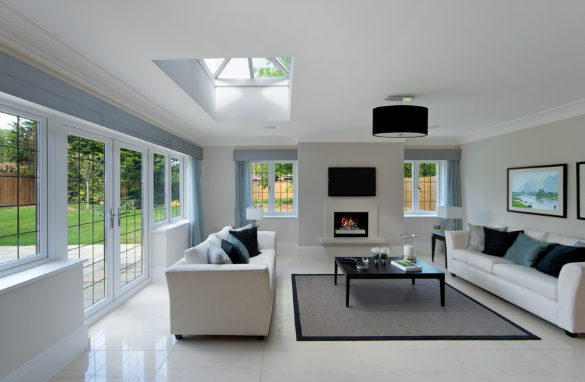 Living room with rectified tile flooring sofa chairs skylight windows glass door