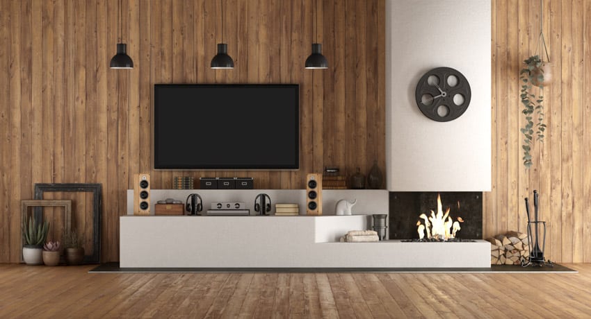 Living room with wood accent wall, fireplace, pendant light, television, and decor