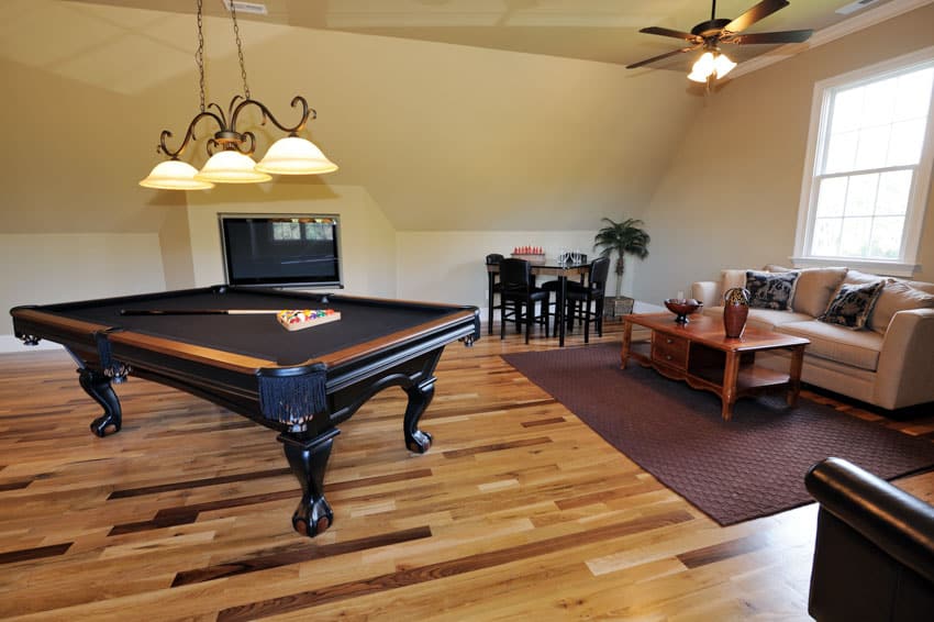 Living room with wood floor, couch, pendant lights, ceiling fan, and pool table