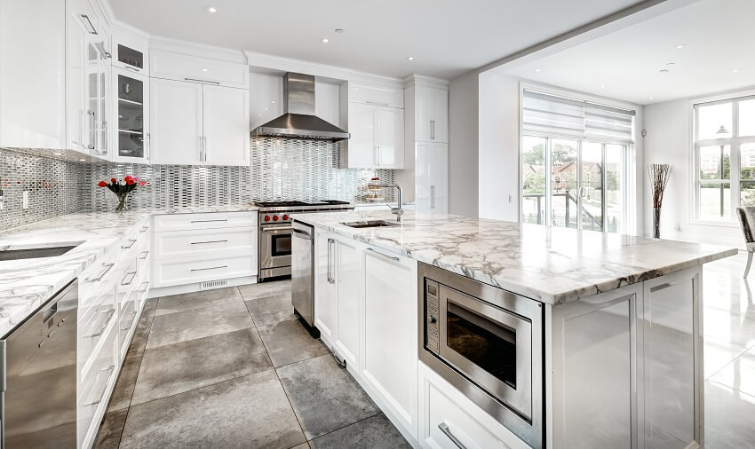 Luxury kitchen with tile floor white cabinets quartz countertops mosaic tile backsplash and island with sink and microwave drawer