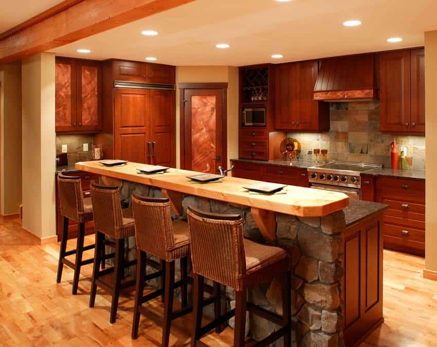 Luxury kitchen with wood floor copper countertops wood cabinets ceiling beam and an island with stools and wood breakfast counter and stone base