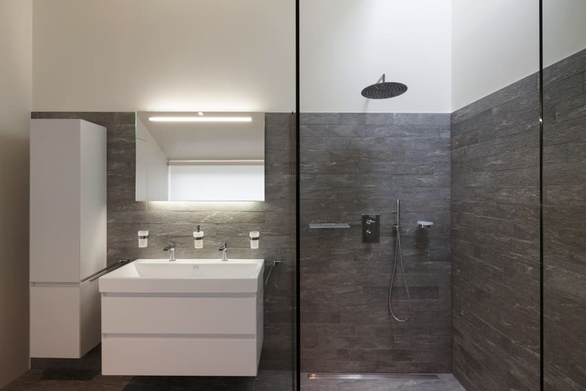 Minimalist bathroom with shower area, window, sink faucets, and accent wall