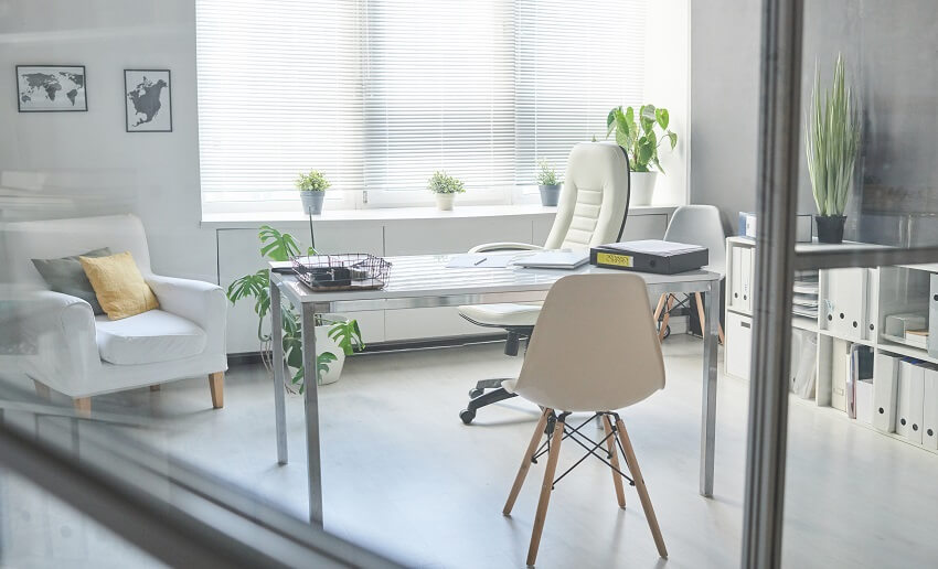 Minimalistic white office interior with filing cabinet office chair metal desk white armchair with throw pillows and windows with blinds and plants