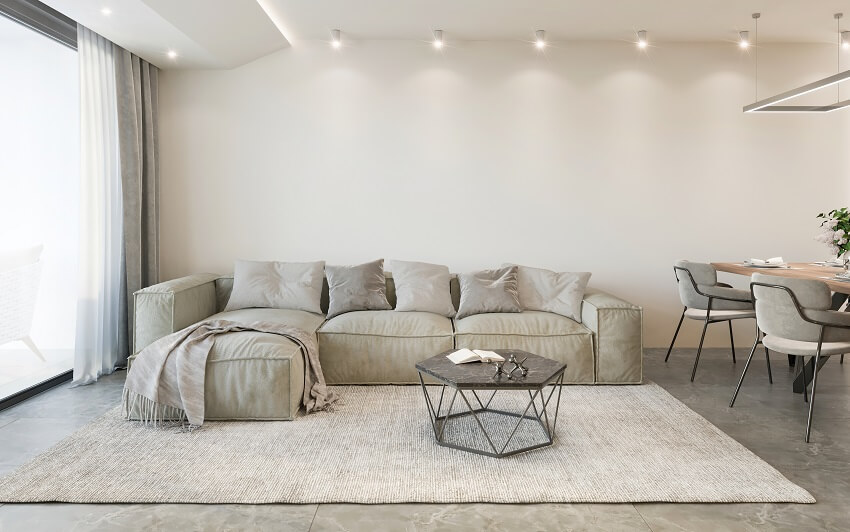 Room with earth colored sofa, white walls, coffee table, natural-fiber rug and lighting fixtures 