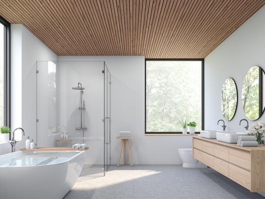 Modern bathroom with ceiling made of wood, tub, mirror, shower area, and windows