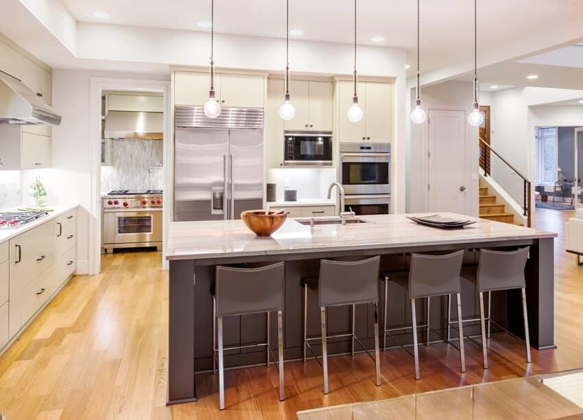 Modern kitchen interior with sink on the off center island cabinets and hardwood floors in new luxury home