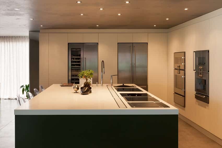 Kitchen with concrete floor, stainless steel appliancews, large island with cooktops and sink