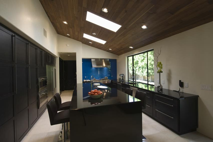 Modern kitchen with slanted ceiling, lighting fixtures, center island, window, cabinets, and countertop