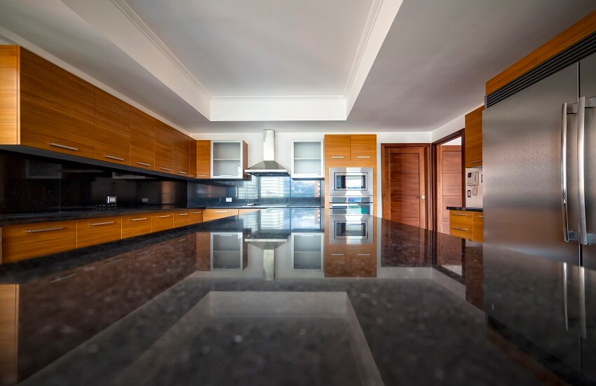 Modern kitchen with stainless steel appliance, brown cabinets and island with black granite