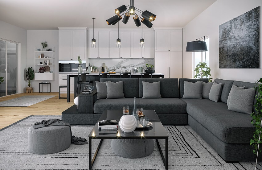 Modern open space kitchen and living room with dark grey sofa carpet coffee table pendant track lights white kitchen cabinets decors and light wood floors