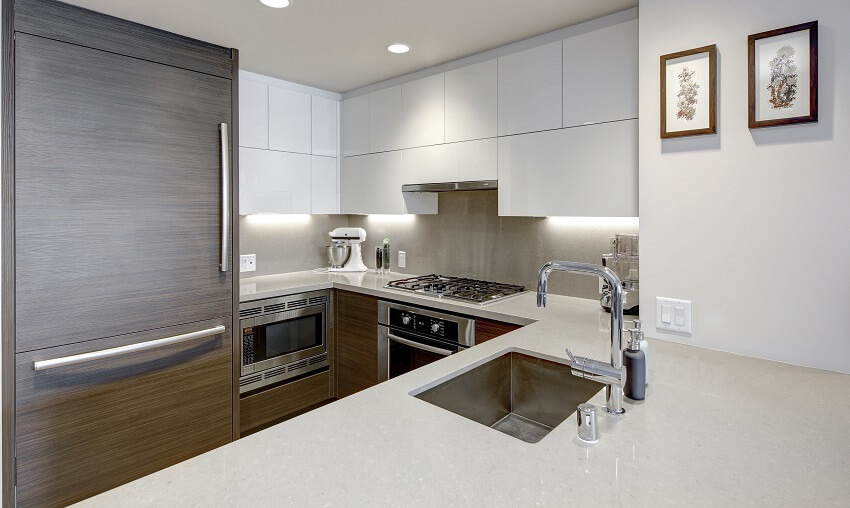 Modern style kitchen with wood paneled refrigerator white cabinets granite countertops and backsplash microwave drawer and under cabinet lighting