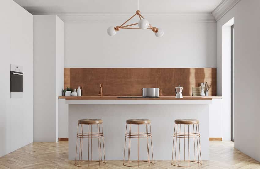 Modern white kitchen interior with copper countertops and backsplash parquet floor pendant light and island with three metal stools
