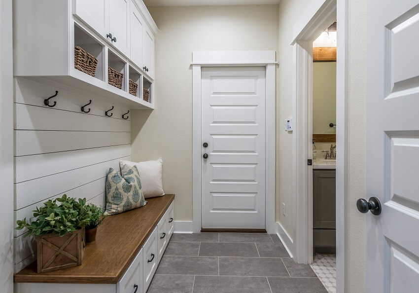 Mudroom with wood bench storage cabinets cream walls and grey tile floors