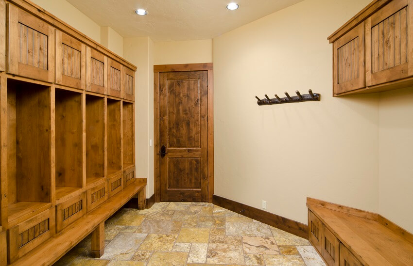 Mudroom with wood storage space and benches cream painted walls coat hooks and slate floors