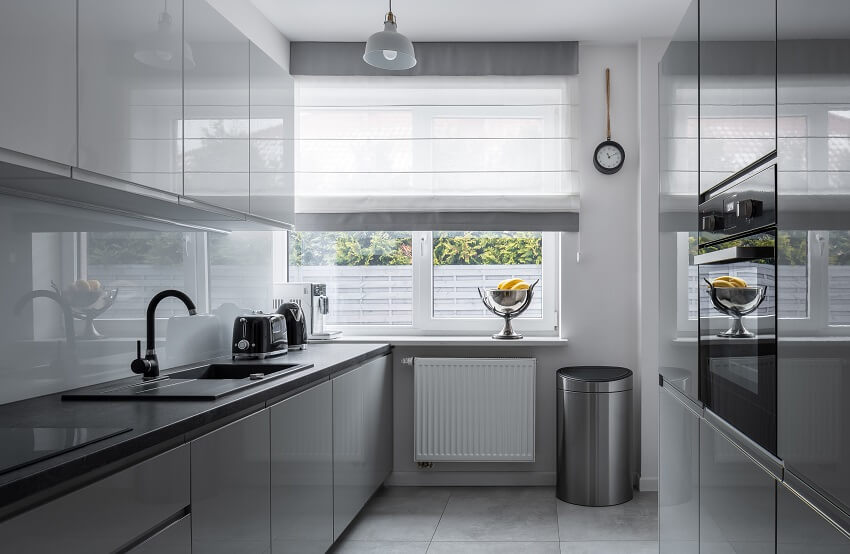 Narrow kitchen with black counters, gray cabinets and tile floor 