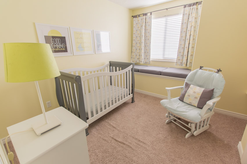 Nursery room with crib, lamp, rocking chair, and window curtain