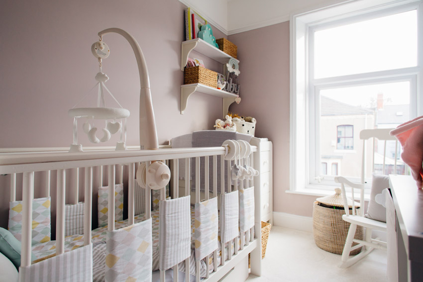 Nursery room with soft peach wall, crib, shelves, and hung window