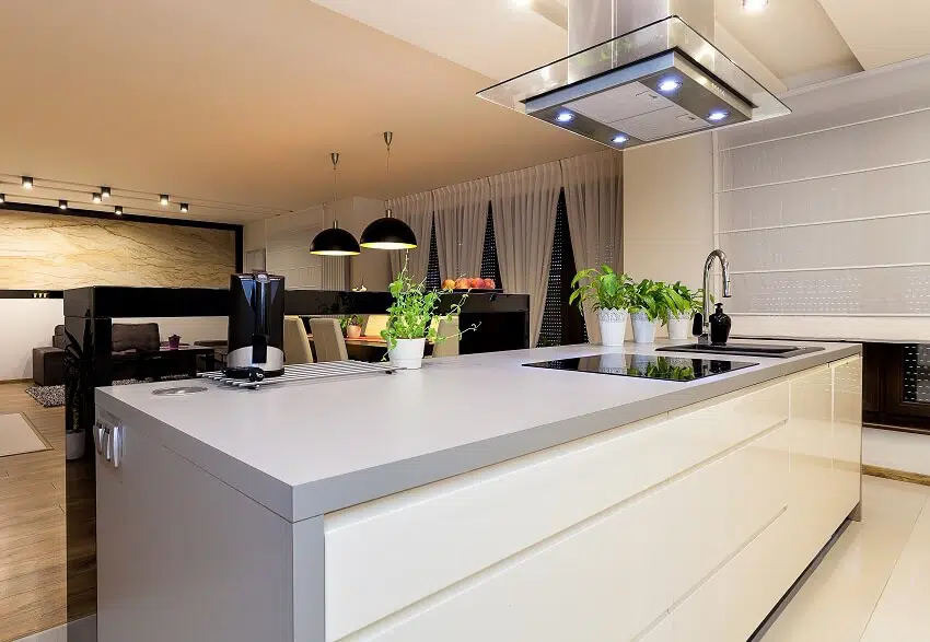 Open kitchen in an apartment features kitchen island with cooktop rangehood and laminate countertop and view of the dining area and living room with panoramic windows