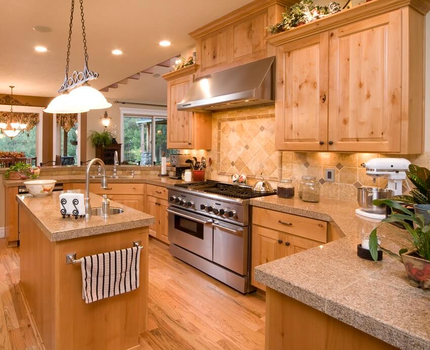 Open kitchen with hickory cabinets tile backsplash and countertops oak floors pendant lights view of the dining area and island with towel bar and sink