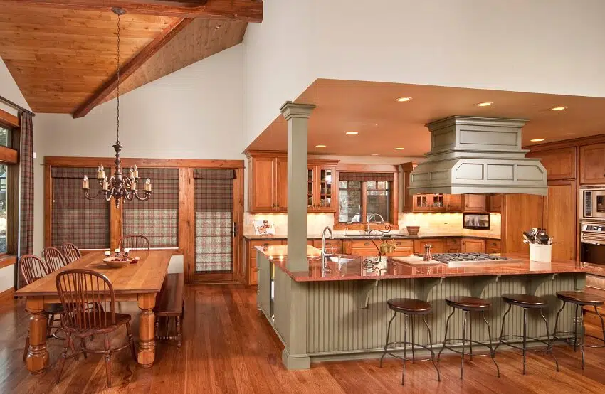 Open kitchen with wood floors ceiling beams large beadboard kitchen island with copper countertops column and sink and view of the dining area